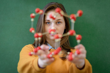 Female student holding molecular structure model. Science class concept.