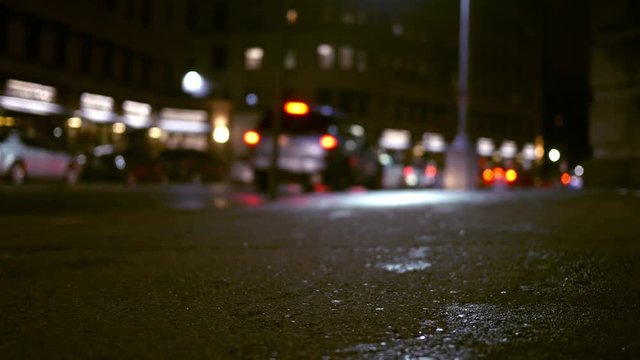 Traffic drives down city street at night in urban town on rainy evening