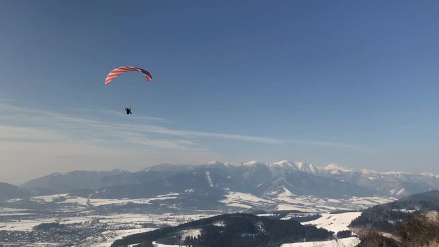 Paraglider flies in the sky on a sunny winter day