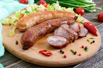 Juicy home made sausage with a light spring salad of fresh vegetables on a wooden tray on the table. A traditional Easter dish.