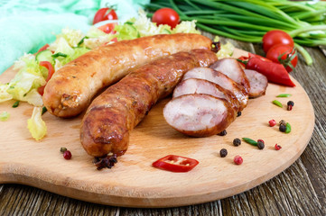 Juicy home made sausage with a light spring salad of fresh vegetables on a wooden tray on the table. A traditional Easter dish.