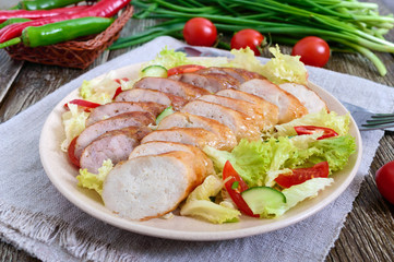 Juicy home made sausage with a light spring salad of fresh vegetables on a wooden table. A traditional Easter dish. Close up