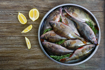 A pile of fresh raw fish on a tray on a wooden background. Top view. Carp. Fresh catch.