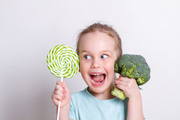 Cute little girl choosing between broccoli and sweets