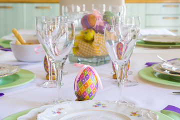 Shot of a set table for a family eastern lunch/dinner. With a colourful egg/eggs, dishes with flowers and wine glasses