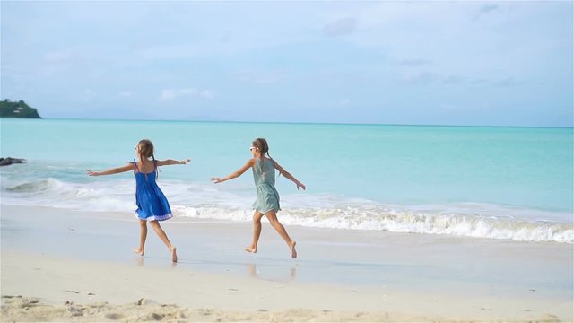 Little happy funny girls have a lot of fun at tropical beach playing together. SLOW MOTION