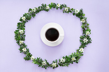Top view of morning cup of coffee in round flowers frame on lilac background, Flat lay style.