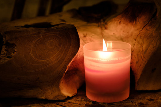 Prayer and hope concept. Retro pink candle light in crystal glass and old wooden