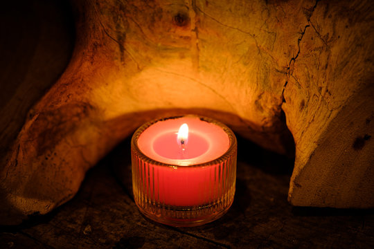 Prayer and hope concept. Retro pink candle light in crystal glass and old wooden
