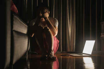 Man facing depression disorder sit on floor with laptop and smartphone beside, conceptual image showing effect from social media resulting in depression disorder