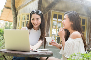 Two teenage women meet in coffee shop use laptop together in afternoon, life style of new teenager