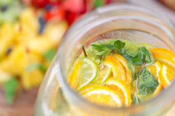 Glass bank of lemonade with sliced citrus fruits on a buffet table. Summer party outdoor. Detox.