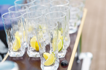 Glass for lemonade with sliced citrus fruits on a buffet table. Summer party outdoor. Detox.