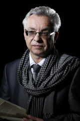 Fototapeta premium Elegant man in glasses with a book in his hands. Portrait of an elderly intelligent man. Elderly man groomed