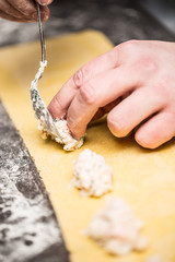 Chef's hands prepares Italian food stuffed pasta ravioli