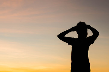 The silhouette of a woman standing looking forward with hope.