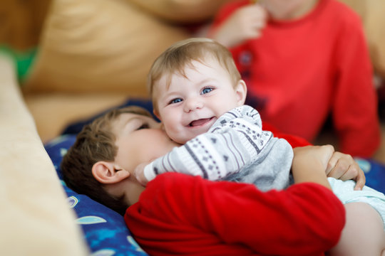 Little kid boy hugging with newborn baby girl, cute sister. Brother on background