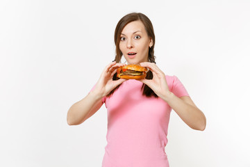 Young beautiful woman in pink t-shirt with braids holding in hands burger isolated on white background. Proper nutrition or American classic fast food. Copy space for advertisement. Advertising area.