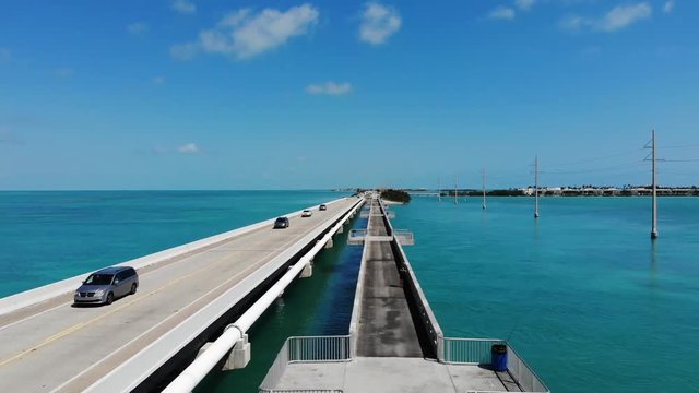 Aerial view of a highway and bridge connecting the Florida Keys. Fisherman and traffic on the bridge. Sunny day with warm blue water.