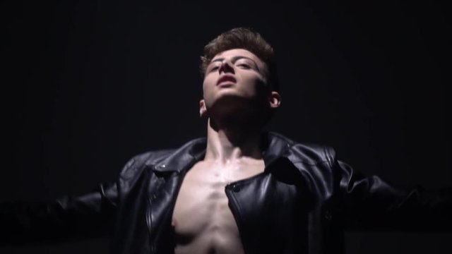A ballet dancer in a leather jacket shows the movements of a ballet