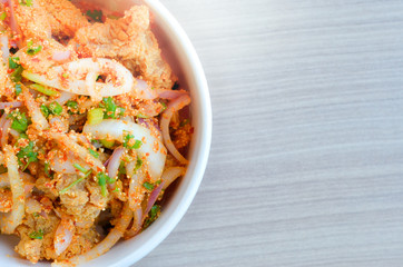 Spicy chicken with rice in bowl on wood background.