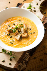 White bowl with pumpkin soup and bread