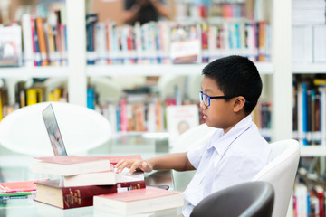 Asian student is searching for knowledge with laptop in the library.