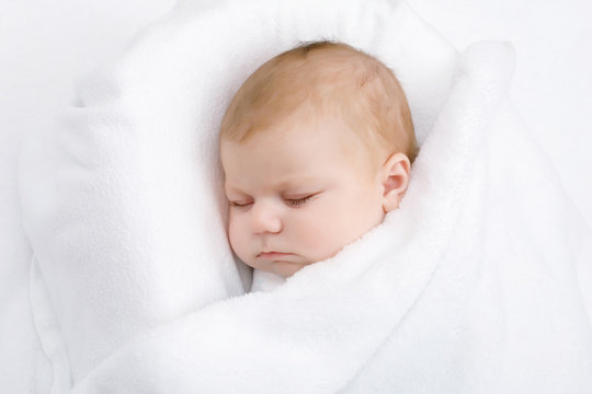 Cute little newborn baby girl sleeping wrapped in blanket