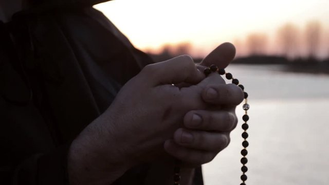 The hand of the priest plucked the rosary in prayer