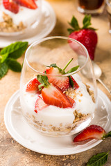 Dessert with strawberries and yoghurt on light brown background. Healthy breakfast food concept.