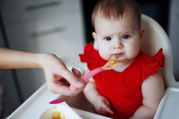 baby in a red dress is sitting on a child's chair