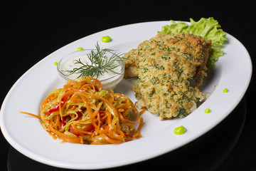 Fried meat in breadcrumbs with stewed carrots and sauce.Eating in a plate. Meat in breading.