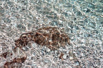 White pebbles and brown rock under crystal clear sea. monk fish shape