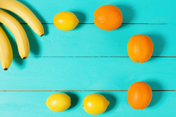 Summer holidays. Frame of oranges and bananas on blue wooden background. Copy space and mock up