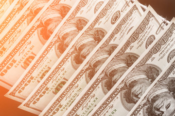 Parts of hundred dollar bills hanging on clerical clips on a rope on the dark background. Closeup, selective focus, toned