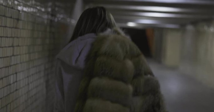 Fashion swag girl wearing fur coat walks in tunnel