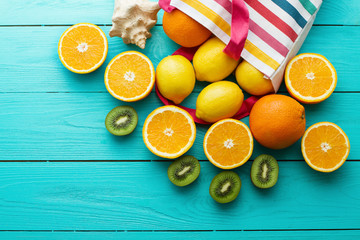 Summer fun time and fruits on blue wooden background. Mock up and picturesque. Orange, lemon, kiwi fruit in bag and shell on the table. © ladyalex
