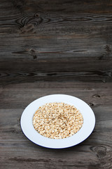 Oatmeal, rolled oats on a plate with glass of milk on white wooden table. 