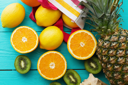 Citrus fresh food. Summer holidays. Orange, kiwi, pineapple, lemon and sea shell on blue wooden background. Vacation and summertime.Top view and copy space. Mock up