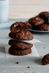 Chocolate cookies for breakfast with hazelnut and a glass of milk on a gray table.