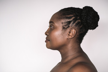 Mature African woman standing sideways against a white background