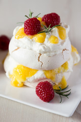 Mango cream and raspberries on pavlova cake