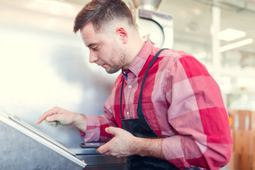 Picture of young man with phone at computer of industrial machine