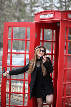 Beautiful young girl in a phone booth. The girl is talking on th
