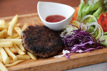 Beef cutlet for steak with fires and vegetables on wood background