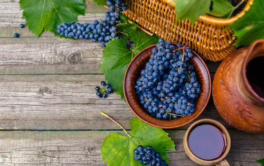 Bowl with grapes beside Jar and cup with wine stand on on rustic wood. Wine making background. Top view