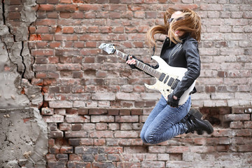  A rock musician girl in a leather jacket with a guitar 