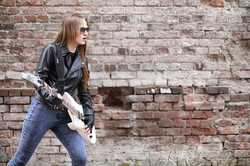  A rock musician girl in a leather jacket with a guitar 