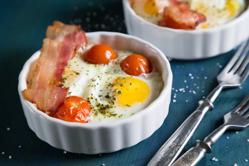 Baked eggs with cherry tomatoes, bacon and greens
