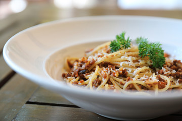 spaghetti Bolognese with minced beef and tomato sauce garnished with parmesan cheese and basil , Italian food